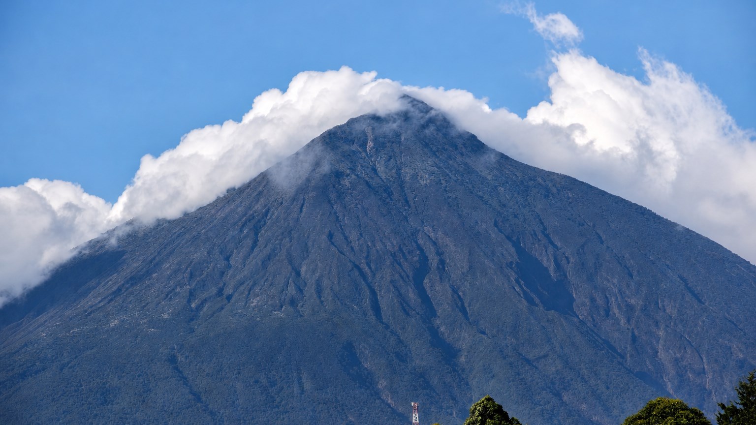 Clouds surrounding a forested mountain peak in Uganda